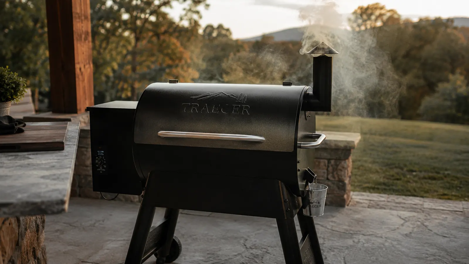 Traeger pellet grill smoking on an Ozark backyard patio at golden hour